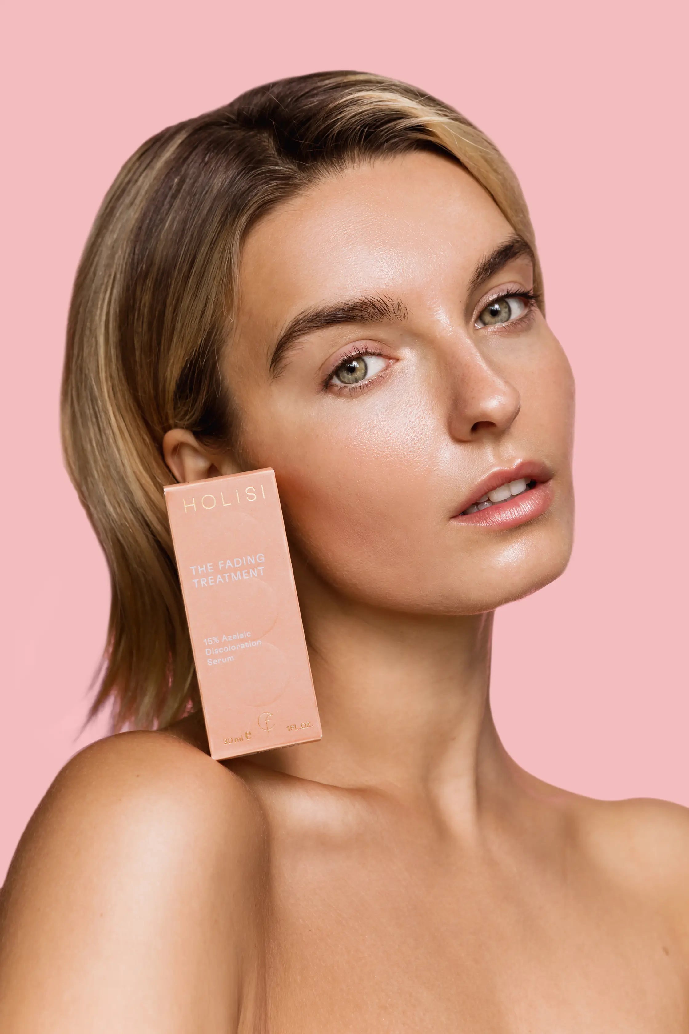 Modelo sosteniendo la caja del sérum antimanchas de Holisi